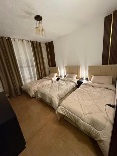 a bedroom with two beds and two tables with lamps at Cozy farm in Jerash
