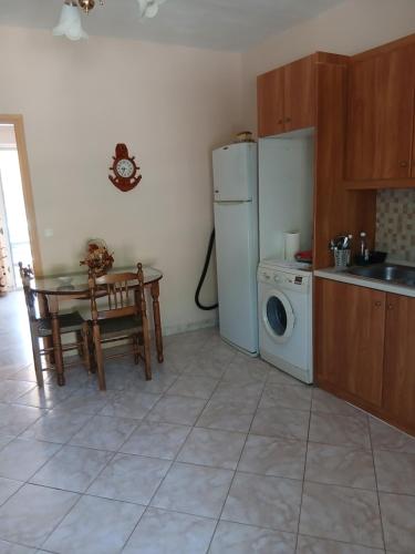 a kitchen with a table and a refrigerator and a washing machine at Nikoletta in Ancient Epidauros