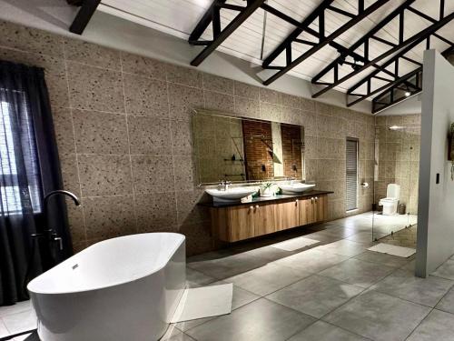 a large bathroom with two sinks and a tub at Fairview Guest House Executive in Hartswater