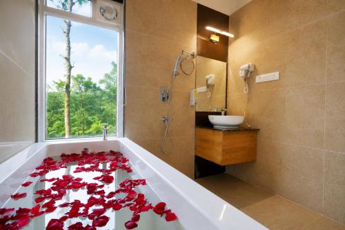 a bathroom with a tub with red flowers on it at Silent Brook Resort - Coorg in Madikeri