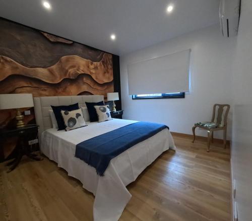 a bedroom with a large bed with a painting on the wall at RR Pico in São Mateus