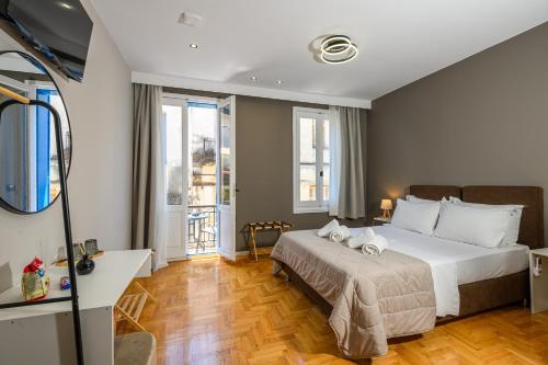 a bedroom with a bed and a desk and windows at Swan Paradise Nafplio in Nafplio