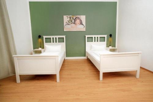 two white beds in a room with a green wall at Shin West in Essen