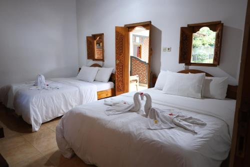a hotel room with two beds with swans on them at The Kori Homestay in Munduk