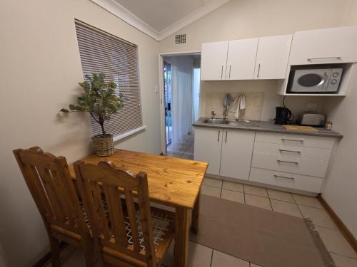 a kitchen with a wooden table and a kitchen with white cabinets at Glendale Cottage in Bloemfontein