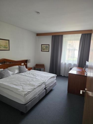 a bedroom with a bed and a desk and a window at Hotel zur Post in Lüdinghausen