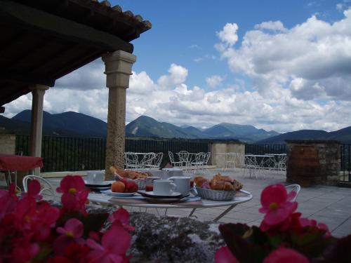 a table with food on it with mountains in the background at Logis Hôtel Les Hospitaliers in Le Poët-Laval
