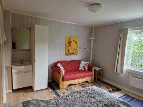 a living room with a red couch and a window at Skorovas Fjellstue in Namsskogan