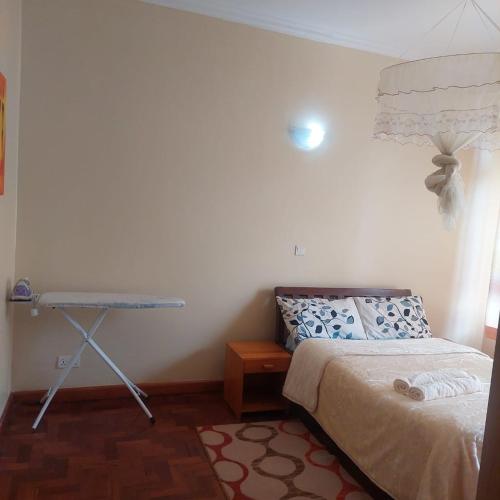 a bedroom with a bed and a table in it at HARMONY GUEST house in Nairobi