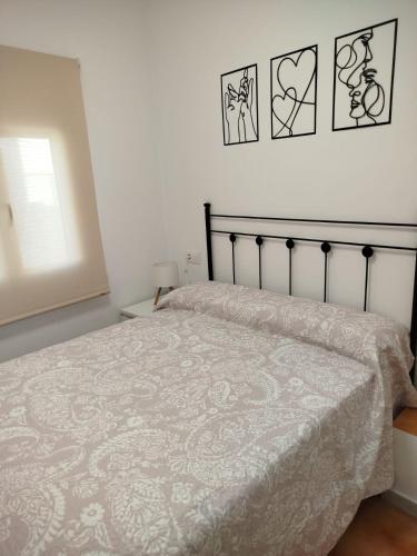 a bedroom with a bed and three pictures on the wall at Aires de Chipiona Apartamento B in Chipiona