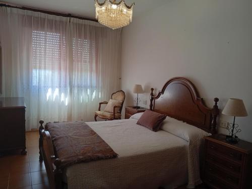 a bedroom with a bed and a chair and a chandelier at Piso centro de Raxò in Raxó