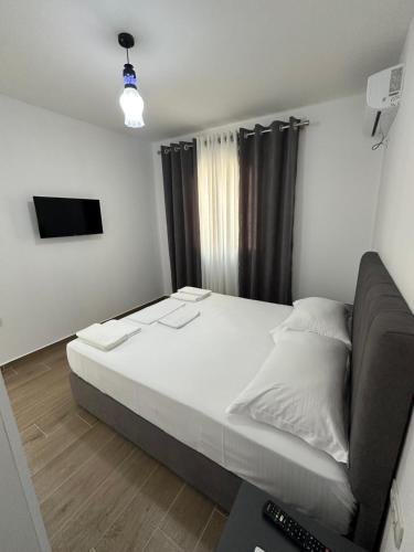a bedroom with a large bed and a television at Arval Rooms in Vlorë