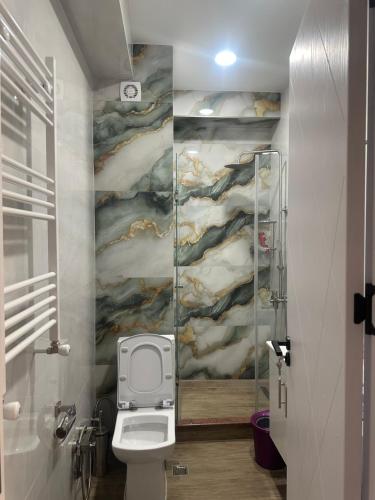 a bathroom with a toilet and a painting on the wall at GM Apartment in Tbilisi City