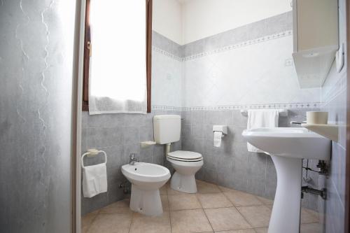 a white bathroom with a toilet and a sink at Residence Smith Sul Mare in Lido degli Estensi