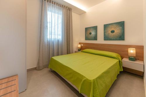 a bedroom with a green bed and a window at VILLA TASSO 25 BILO in Lido degli Estensi