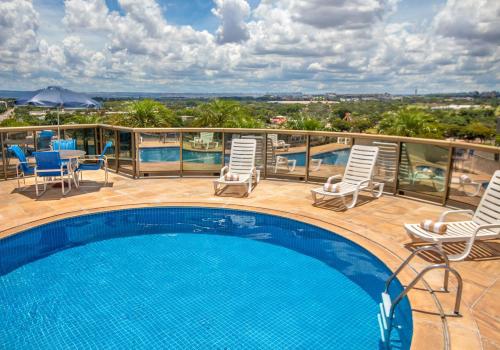 a swimming pool on a balcony with chairs and a table at Hotel Brasil 21 Suites, Affiliated by Meliá in Brasília