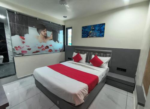 a bedroom with a large bed with red pillows at Hotel Satyam in Vadodara