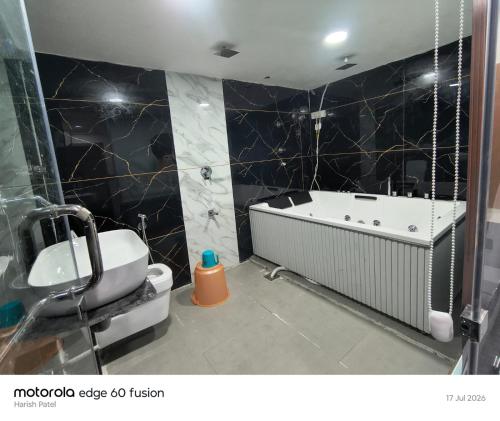a bathroom with a bath tub and a sink at Hotel Satyam in Vadodara