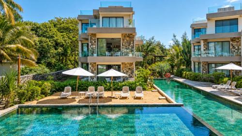 a swimming pool with chairs and umbrellas in front of a building at PARATY Apartment l Complex Ocean Terraces in Poste Lafayette