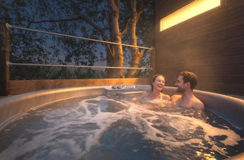 a man and a woman sitting in a hot tub at Hideaway by Liv Retreats in Lincoln