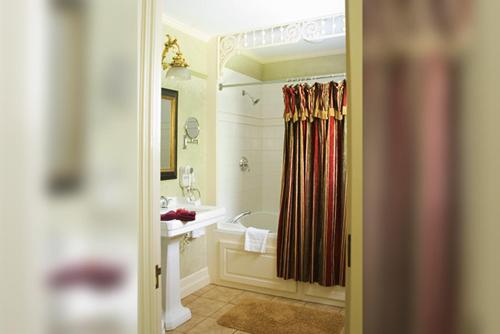 a bathroom with a tub and a shower curtain at Cornerstone Victorian Bed and Breakfast in Warrensburg