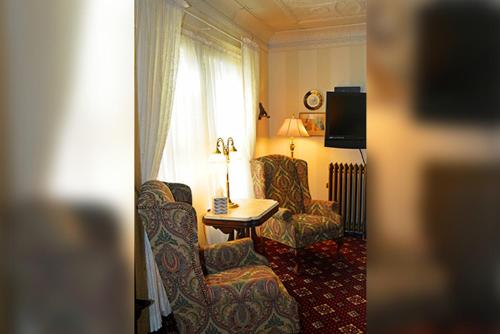 a hotel room with a chair and a table and a window at Cornerstone Victorian Bed and Breakfast in Warrensburg