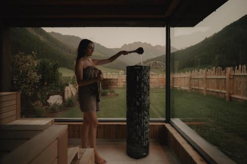 a woman standing in front of a window holding a brush at FRÄULEIN NANNERL - Boutique Apart mit Saunahaus in Gerlos