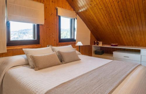 a bedroom with a large white bed with two windows at Villa Aldán Areacova in Aldán