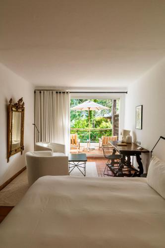 a hotel room with a bed and a table and chairs at Grand Hôtel De Cala Rossa & Spa Nucca in Porto-Vecchio