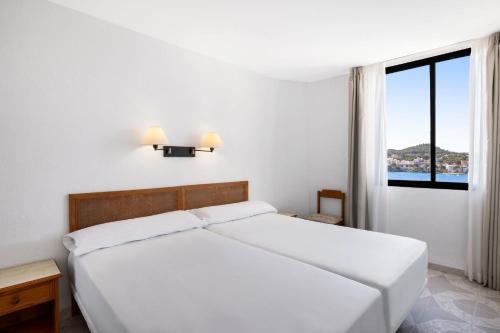 a white bedroom with a bed and a window at TRH Jardín Del Mar in Santa Ponsa