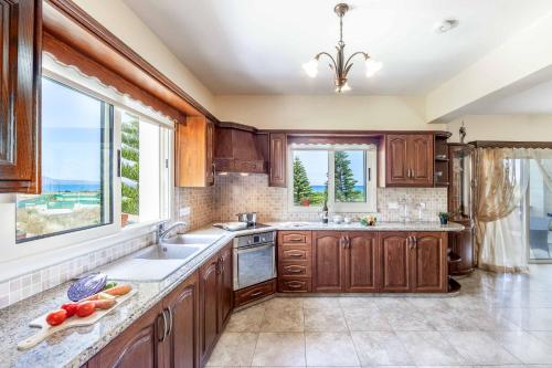 a kitchen with wooden cabinets and a large window at Villa Vasilissa in Argaka