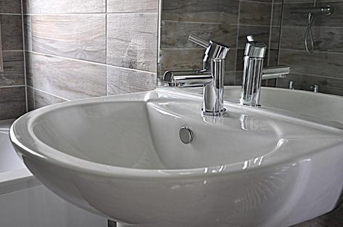a white sink in a bathroom with a tub at Riverside Holiday Park in Amberley