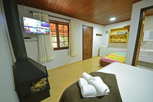 a room with a fireplace and a bed with a tv at Alta Colina Chalés in São Pedro da Serra
