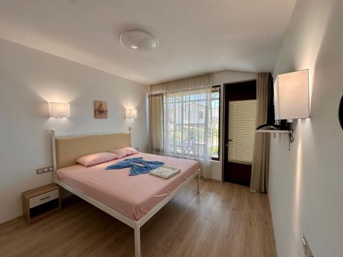 a bedroom with a bed with pink sheets and a window at Бунгала " SEA VILLAGE DAR " in Kamchia