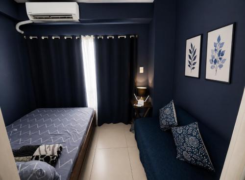 a bedroom with blue walls and a bed and a window at Dan's Cool Suites Tagaytay in Tagaytay