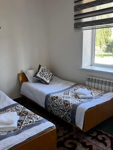 two beds in a room with a window at ERLAN Guest House in Jangy-Talap