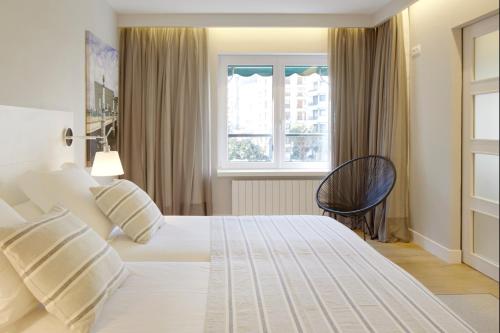 サン・セバスティアンにあるBella Easo 3 by FeelFree Rentalsの白いベッドと窓が備わるホテルルームです。