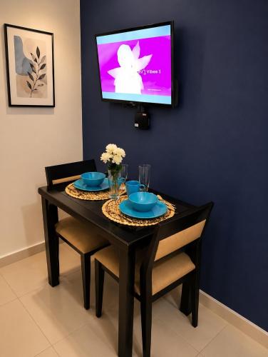 a dining room table with blue plates and a tv on a wall at Dan's Cool Suites Tagaytay in Tagaytay