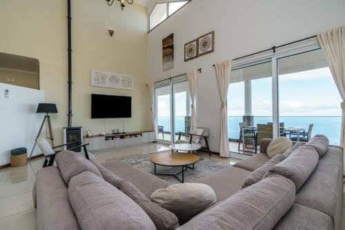 a living room with a large couch and a television at Villa Sea Colors by An Island Apart in Arco da Calheta