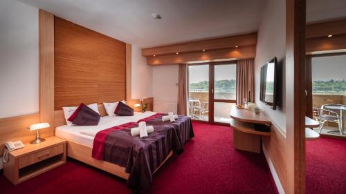 a hotel room with a bed and a balcony at Hotel Corvus Aqua in Orosháza