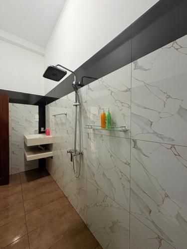 a bathroom with a shower with white marble tiles at Danketiya Palace in Ahangama