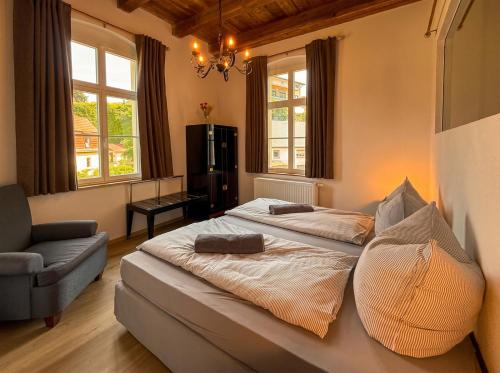 a bedroom with two beds and a chair and windows at Wauermühle in Lohmen