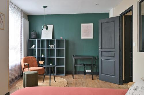 a room with a green wall with a table and chairs at Brunhilde in Montivilliers