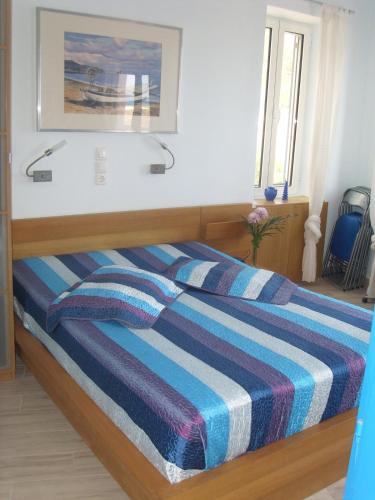 a bedroom with a bed with a striped blanket at Alkistis Apartments, 1st floor in Agios Kirykos