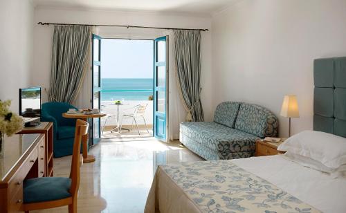 a hotel room with a bed and a balcony with the ocean at Mitsis Norida in Kardamaina