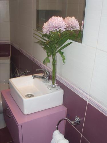 a bathroom with a sink and a vase with pink flowers at Alkistis Apartments, 1st floor in Agios Kirykos