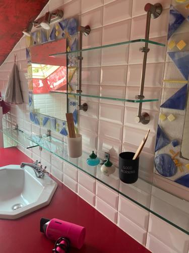 a bathroom with a sink and a counter with glass shelves at chambre deux personnes, lit pour Bébé in Verlhac-Tescou