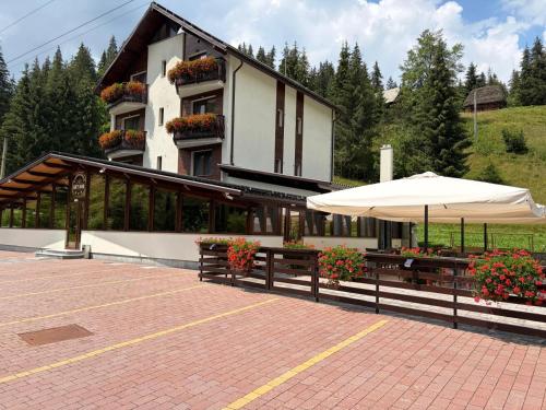 a building with two benches and an umbrella at PENSIUNEA SKY HUB in Arieşeni