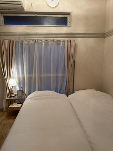 a pair of beds in a bedroom with a window at Guest House "Ro"Hieda B101 in Shimonoseki