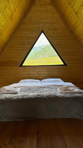 a bed in a wooden room with a window at Lunara Chalet in Kazbegi